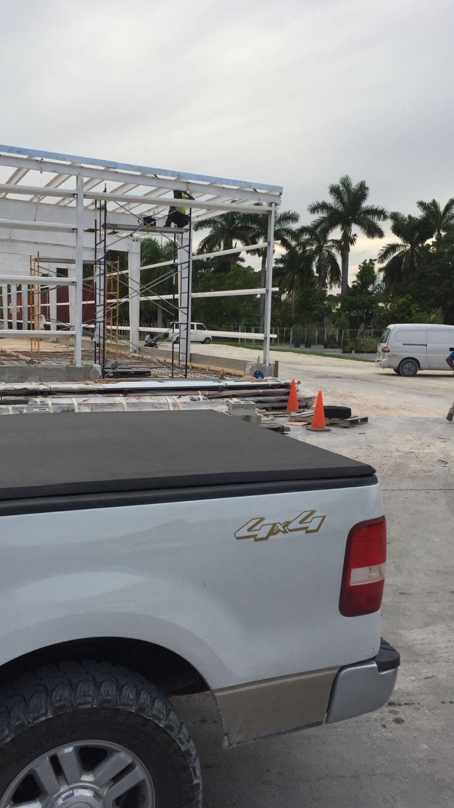 Steel frame structure under construction with palm trees