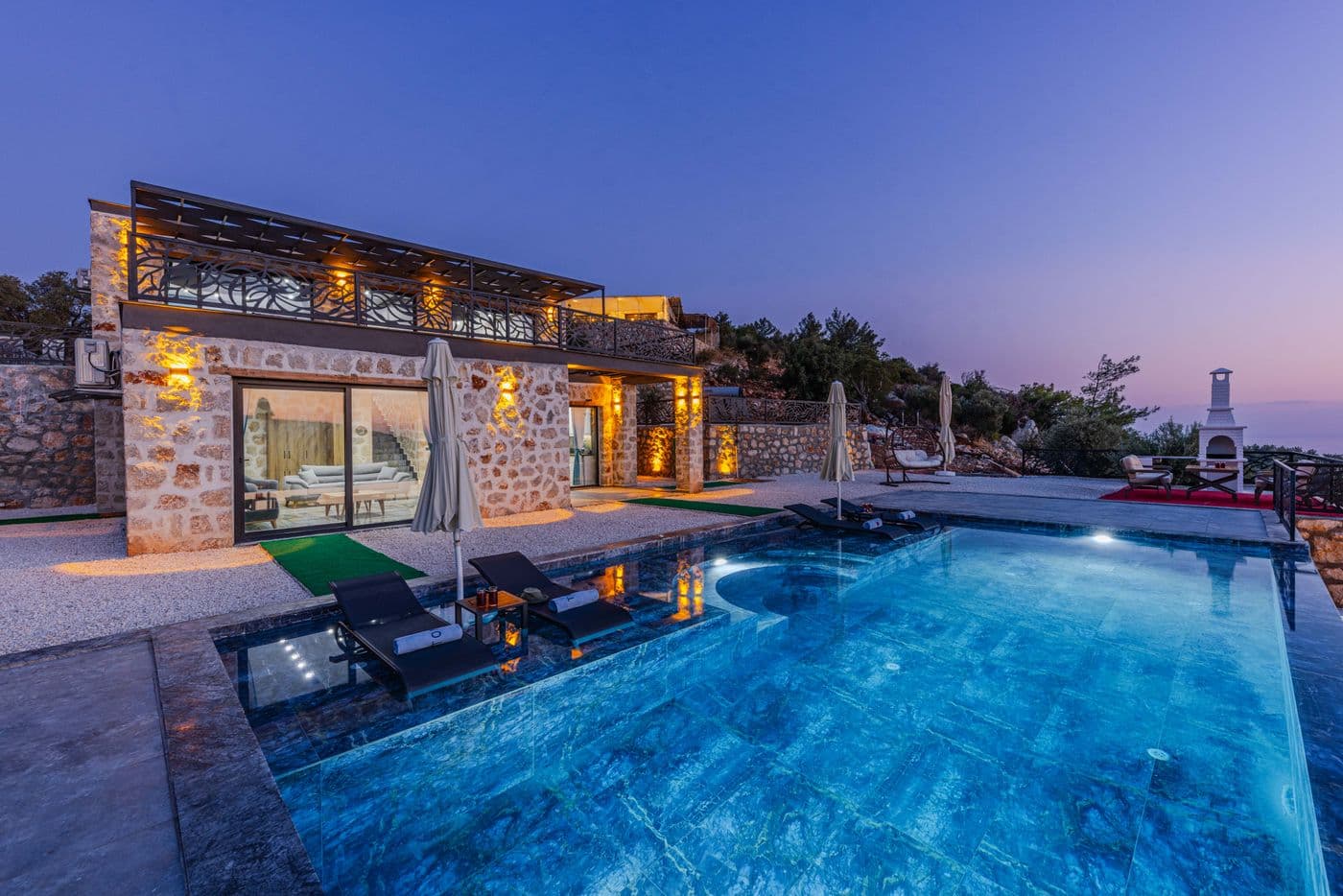 Stone estate with lit pool at dusk